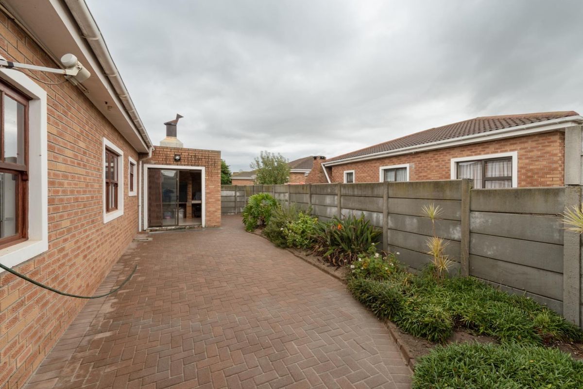 Rear exterior view of the townhouse featuring brick paving, a built-in braai area, and a precast concrete boundary wall.