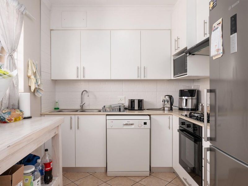 A functional kitchen featuring white cabinetry, laminate countertops, a built-in oven with gas hob, and tiled flooring, offering a clean and practical workspace.