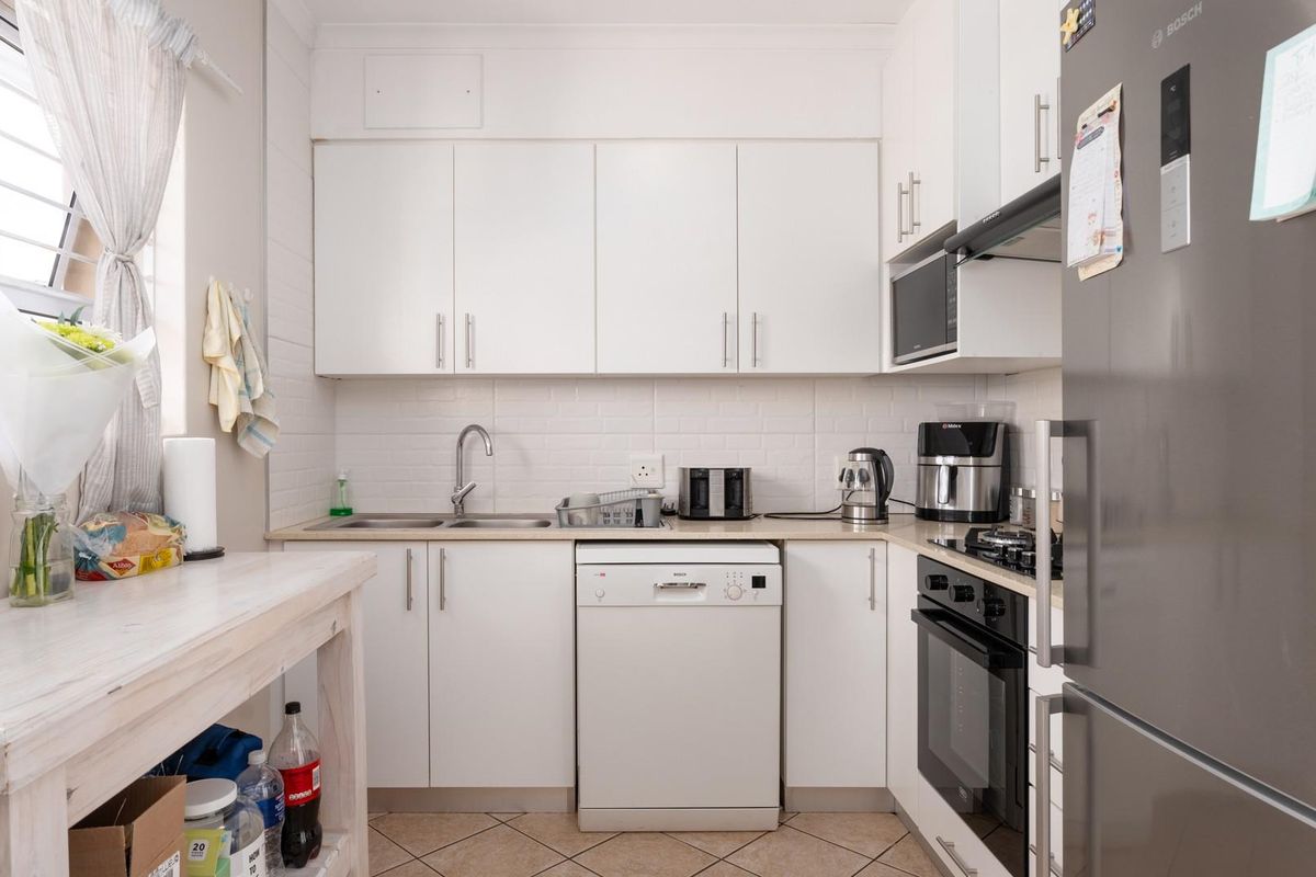 A functional kitchen featuring white cabinetry, laminate countertops, a built-in oven with gas hob, and tiled flooring, offering a clean and practical workspace.