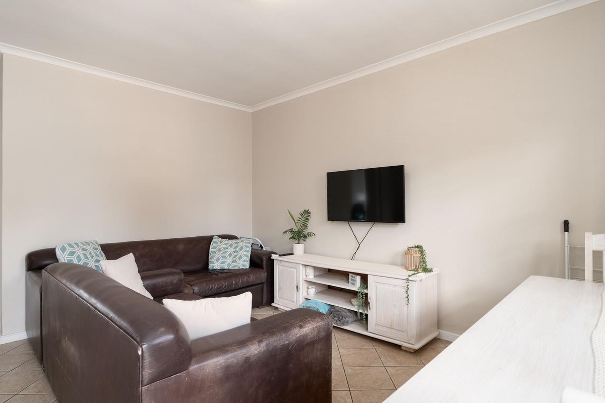 A functional living room featuring neutral wall tones and tiled flooring, providing a comfortable and versatile space for relaxation.