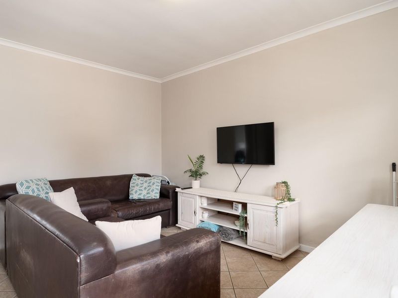 A functional living room featuring neutral wall tones and tiled flooring, providing a comfortable and versatile space for relaxation.