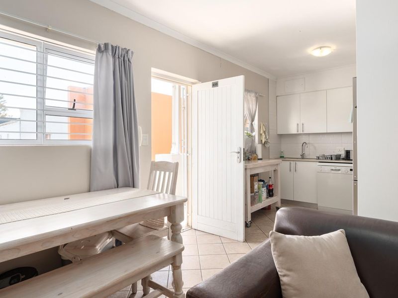 Open plan living and kitchen area featuring tiled flooring, white cabinetry, and direct access to an outdoor space.