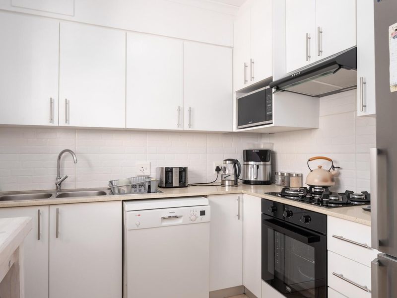 A well-maintained kitchen featuring white cabinetry, a tiled backsplash, built-in oven, gas hob, and integrated extractor fan.