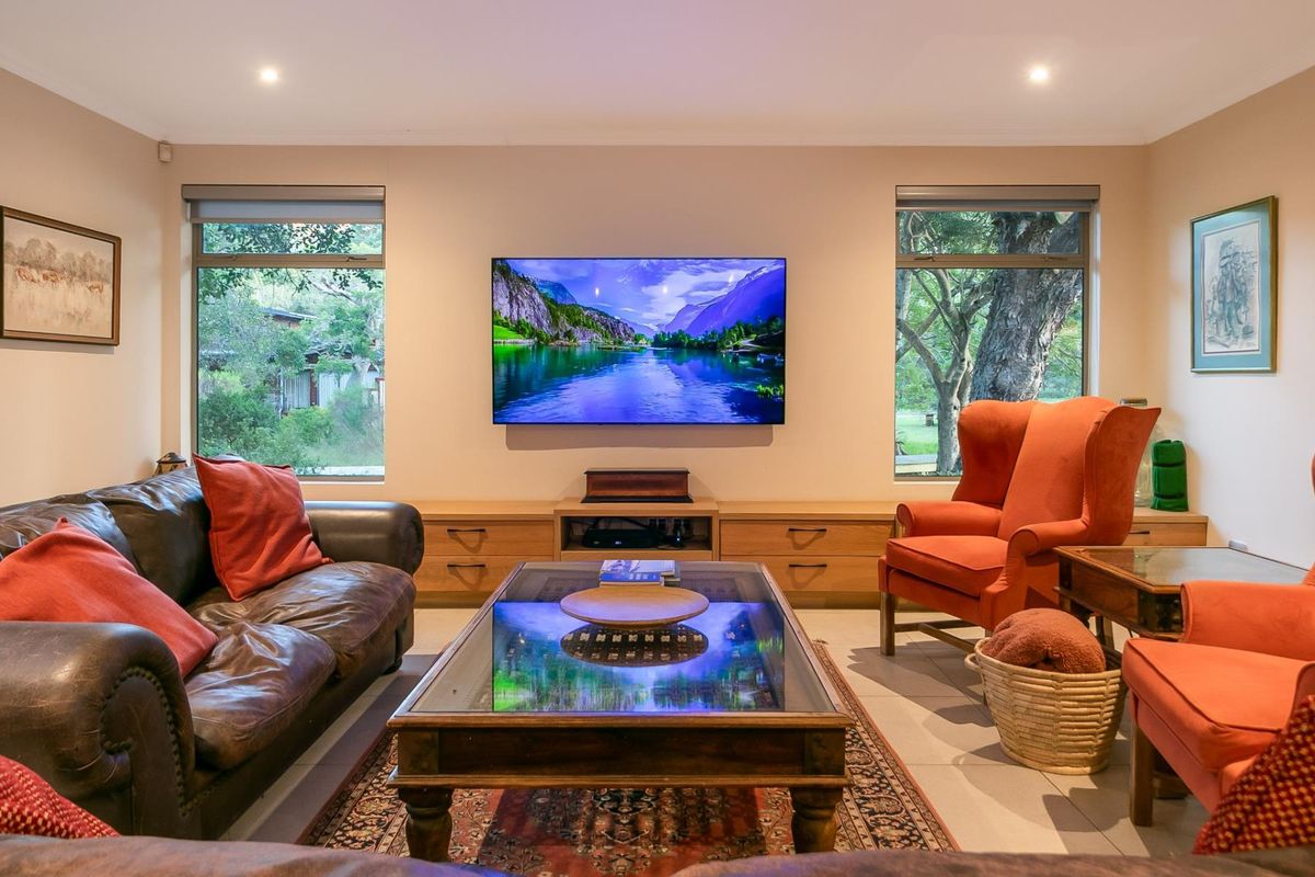 A well-maintained living room featuring large windows with garden views, recessed downlighting, and built-in cabinetry.