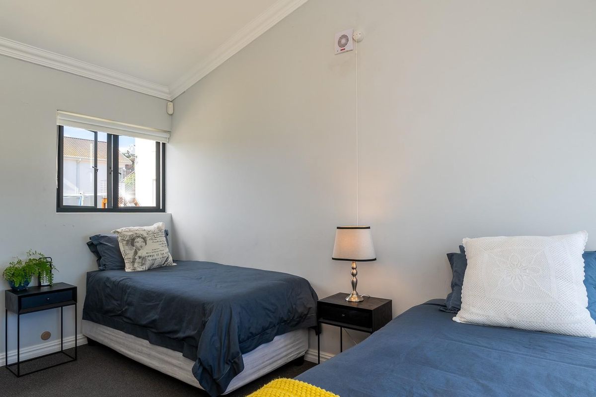 A bright bedroom featuring a vaulted ceiling, neutral wall finishes, and a window with a roller blind.