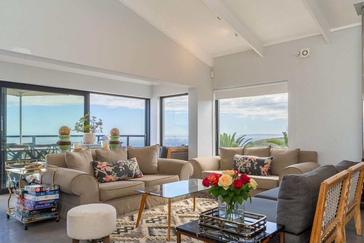 Spacious living room featuring a vaulted ceiling, large sliding glass doors, and a built-in wood-burning fireplace with scenic coastal views.