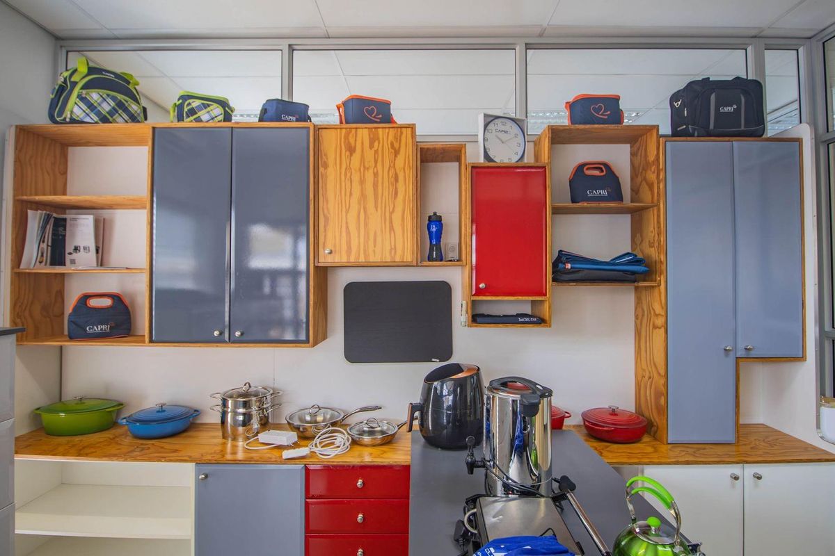 A functional office kitchenette featuring a mix of wood-grain and colored cabinetry, providing ample storage and workspace for staff convenience.
