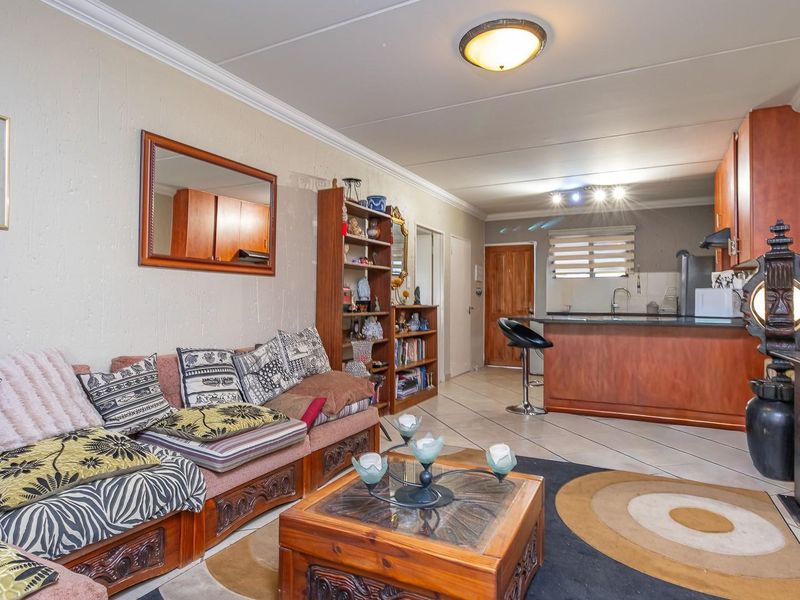 Open-plan living area featuring a kitchen with a breakfast bar island and tiled flooring throughout, creating a functional and connected living space.