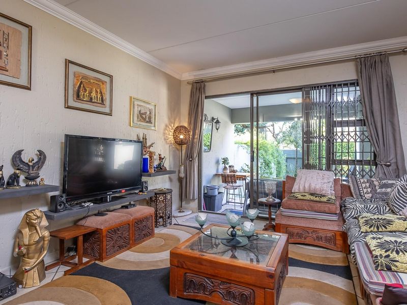 A comfortable living room featuring tiled flooring, decorative coving, and a large sliding glass door that provides access to an outdoor patio area.