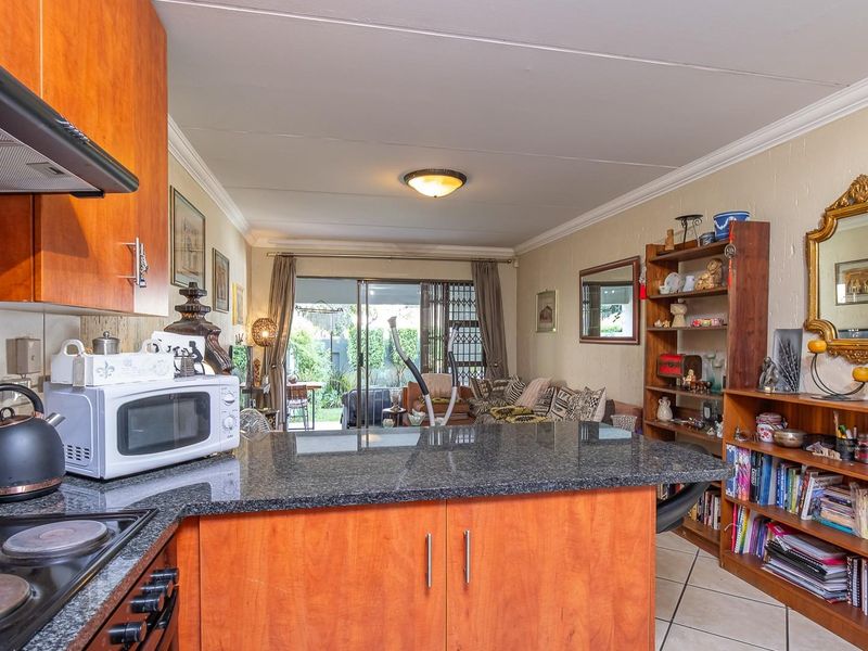 Open-plan kitchen and living area featuring granite countertops, wood cabinetry, and sliding glass doors leading to an outdoor patio space.