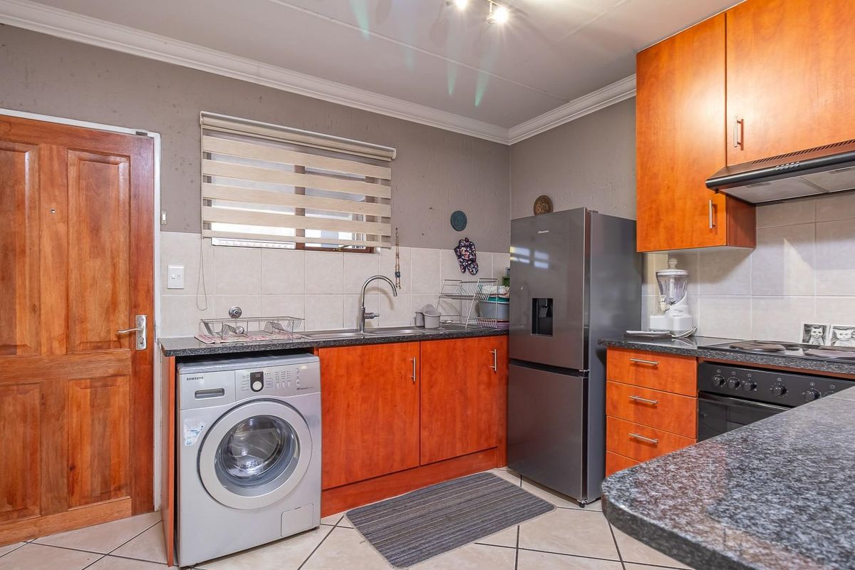 Functional kitchen featuring wood-finish cabinetry, granite countertops, tiled backsplash, and integrated appliances, offering a practical layout for daily use.