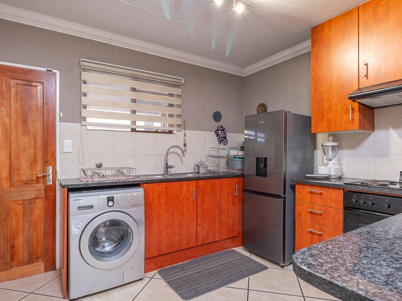 Functional kitchen featuring wood-finish cabinetry, granite countertops, tiled backsplash, and integrated appliances, offering a practical layout for daily use.