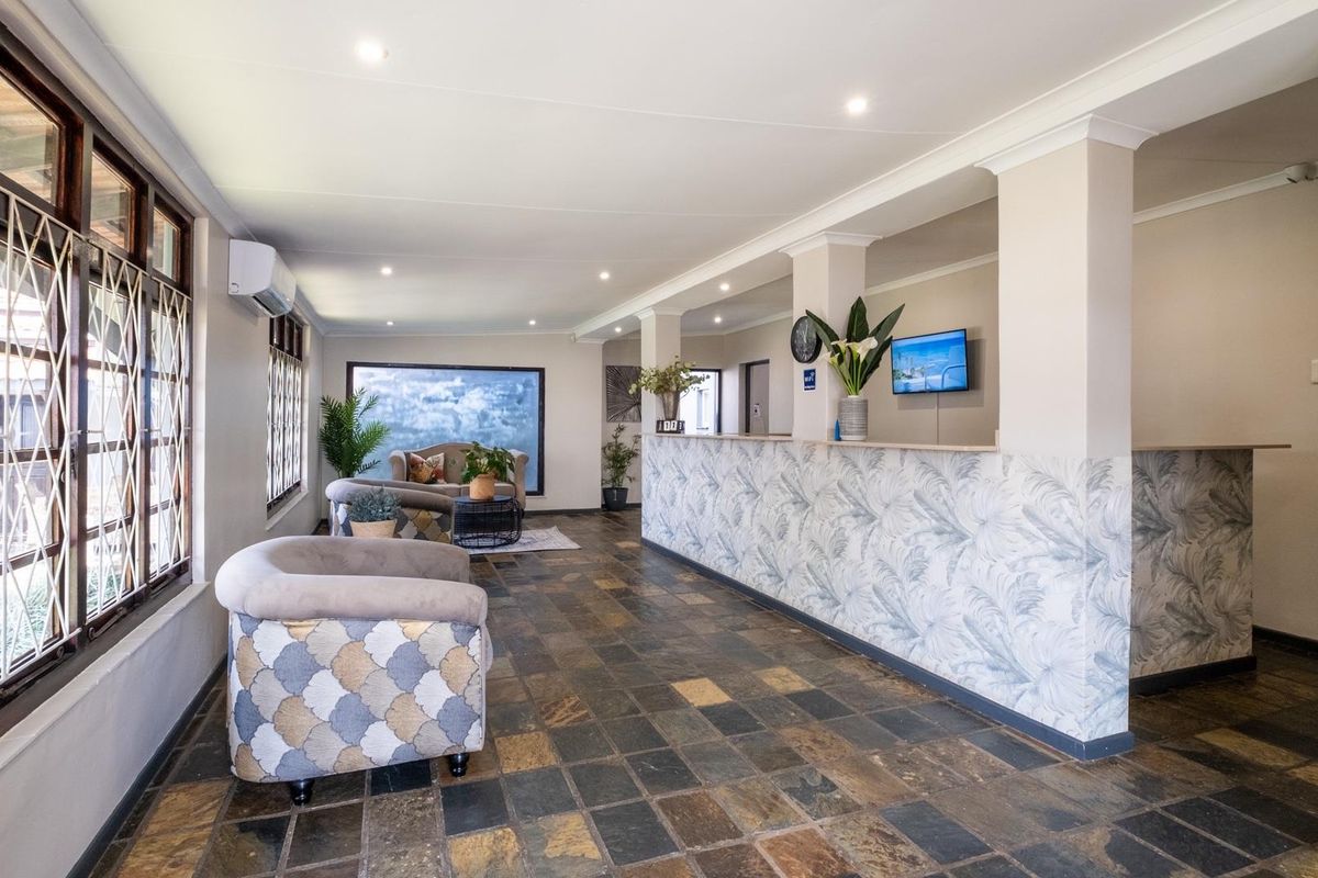 Spacious reception or living area featuring slate tile flooring, a built-in service counter with decorative wallpaper, and recessed ceiling lighting.