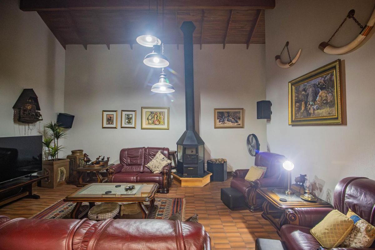 Spacious living room featuring a high vaulted timber ceiling, terracotta tiled flooring, and a prominent central freestanding fireplace.