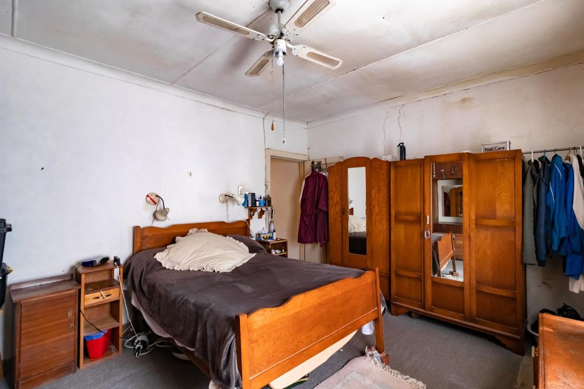 A bedroom featuring a ceiling fan and carpeted flooring, requiring cosmetic updates and repairs to the ceiling and wall finishes.