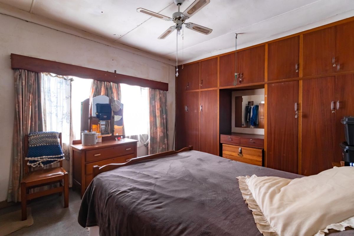 A bedroom featuring extensive built-in wooden cabinetry and a ceiling fan, requiring cosmetic updates to modernize the space.