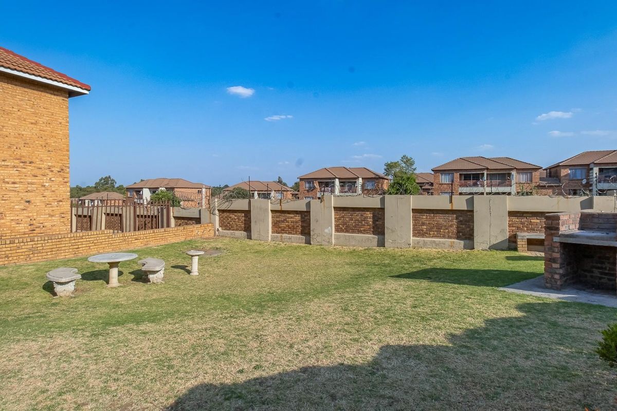 A private rear garden area featuring a built-in brick braai and perimeter walling with security fencing.