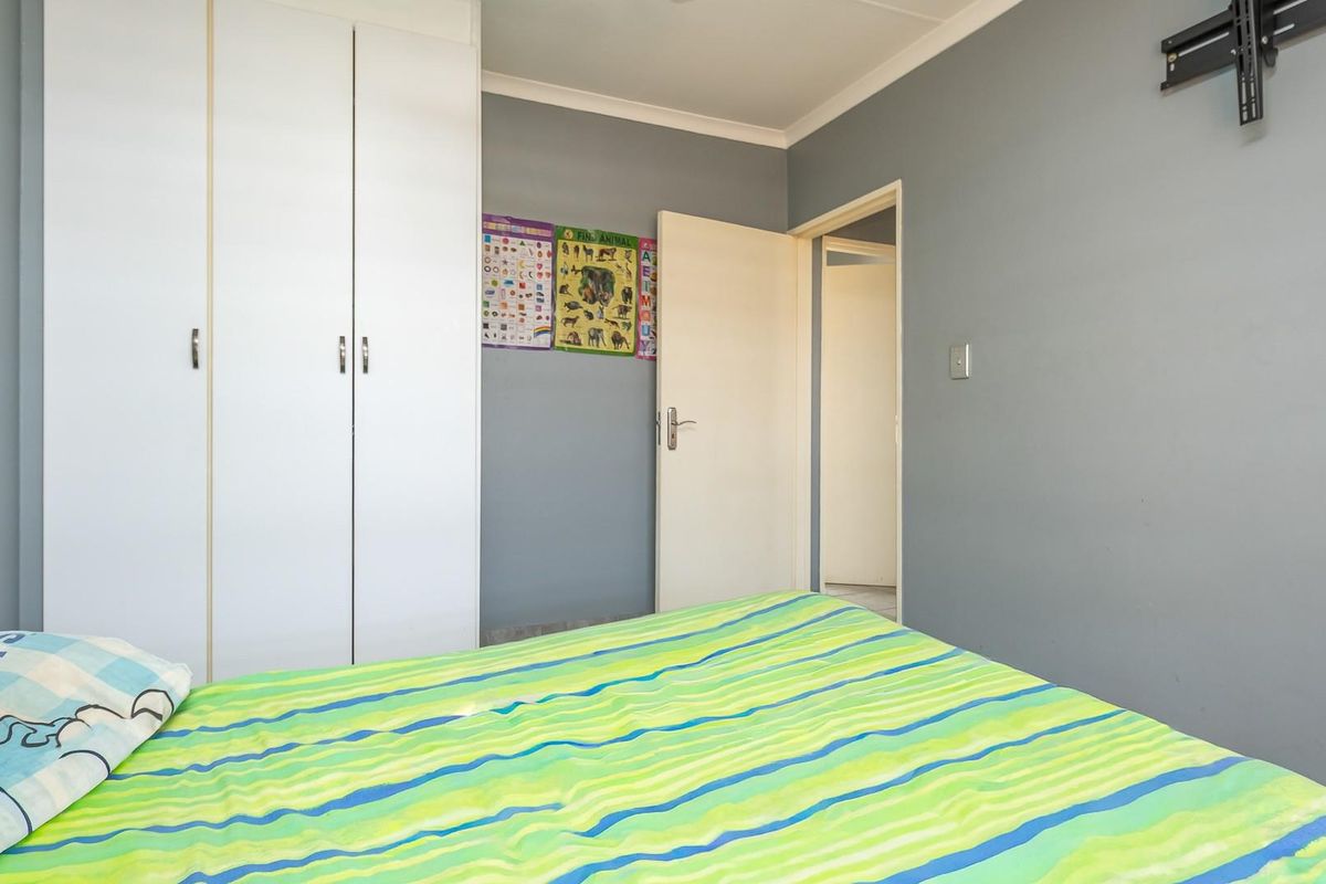 A bedroom featuring built-in white cupboards, grey painted walls, and a standard door leading to the hallway.