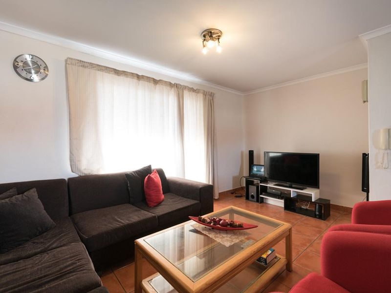 A comfortable living room featuring terracotta floor tiles, coved ceiling cornices, and a wall-mounted intercom system.