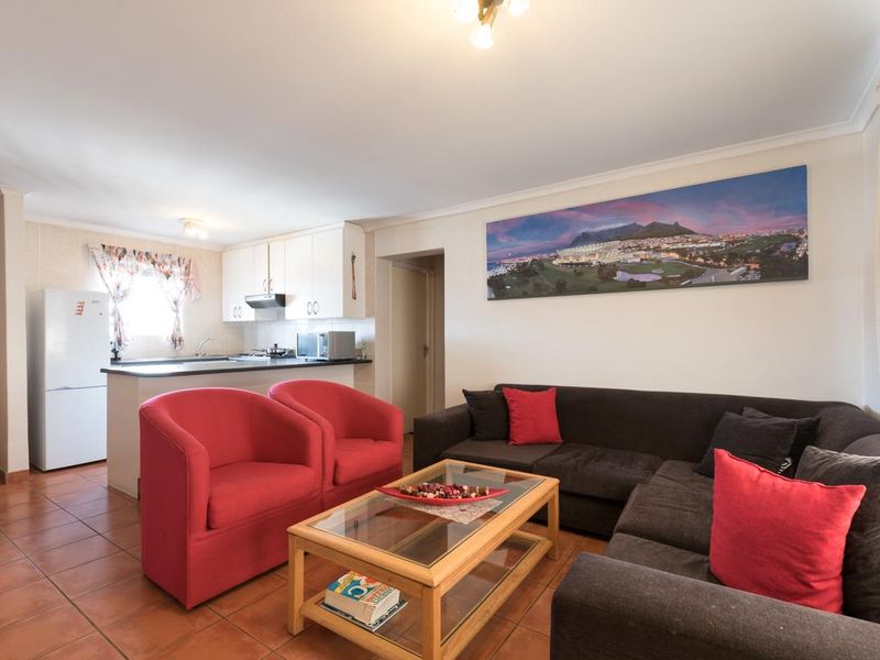 Open-plan living area featuring tiled flooring and a functional kitchen with built-in cabinetry and an extractor fan.