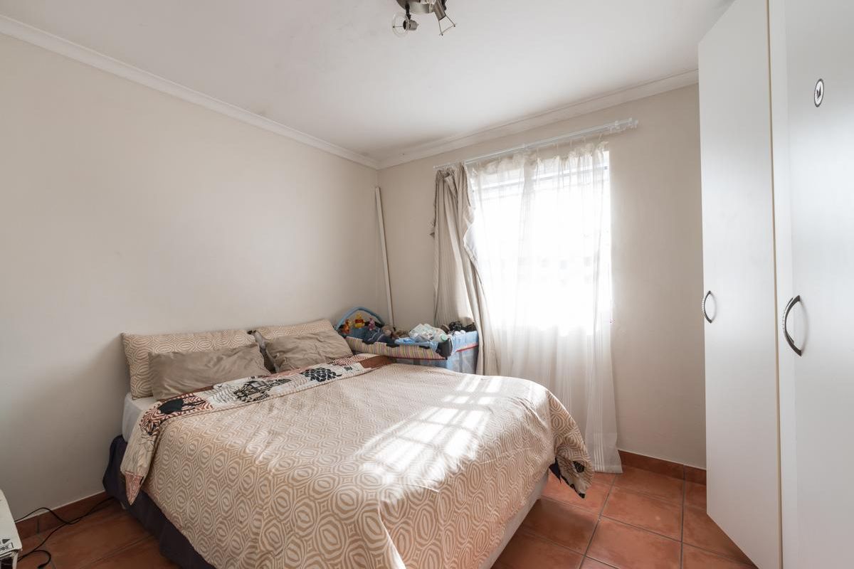 A functional bedroom featuring tiled flooring, a built-in wardrobe, and natural light from the window.