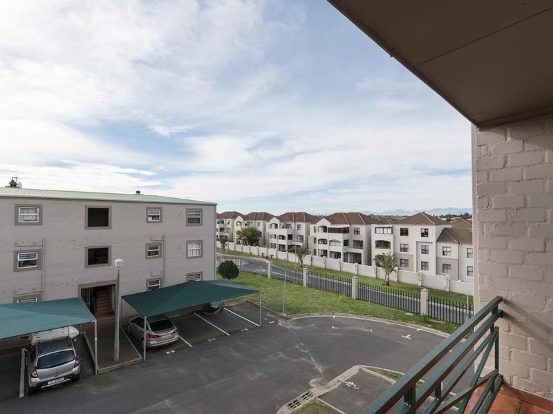 View from a balcony overlooking the apartment complex parking area and surrounding residential buildings.