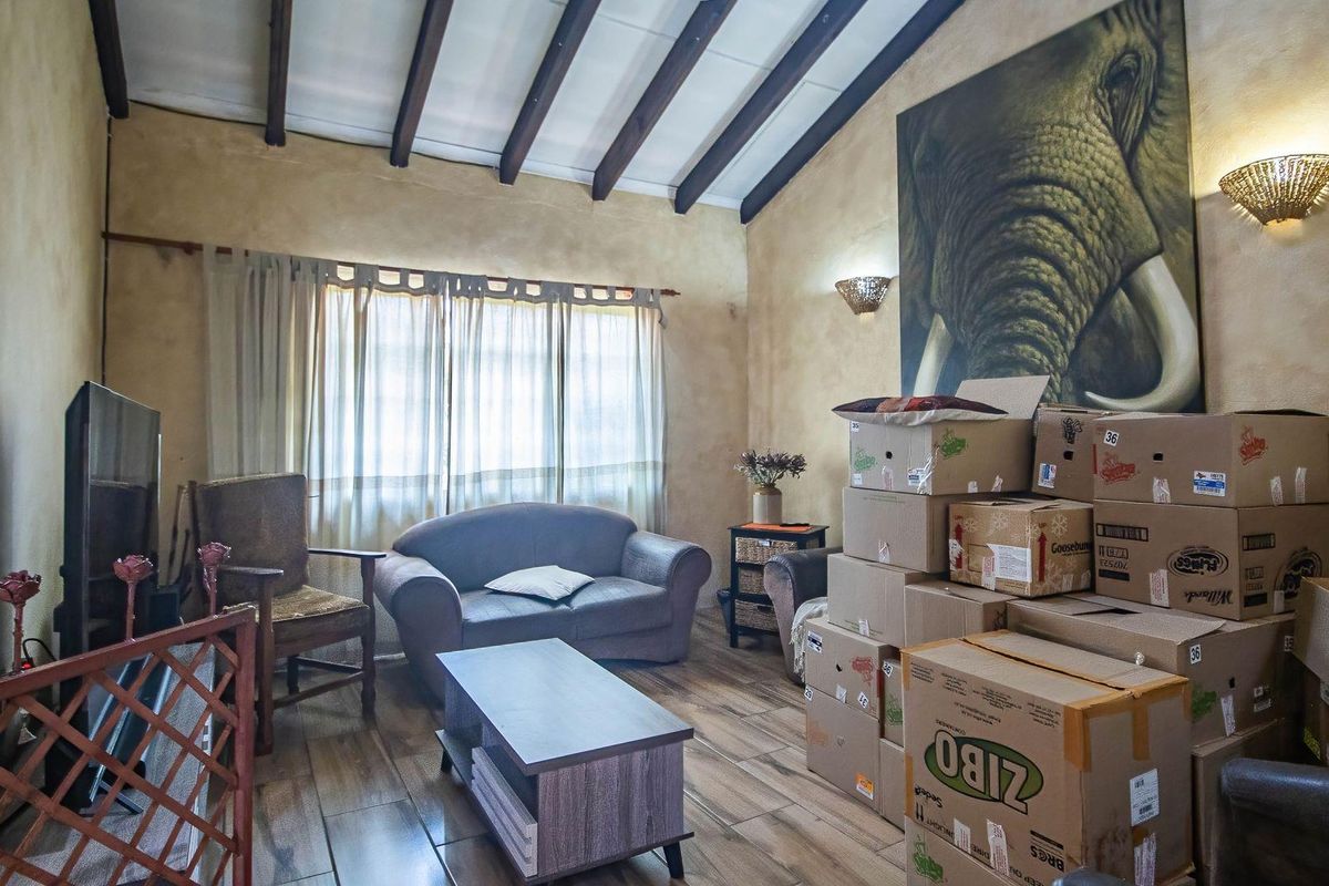A living room featuring exposed timber ceiling beams, textured wall finishes, and wood-look tiled flooring.