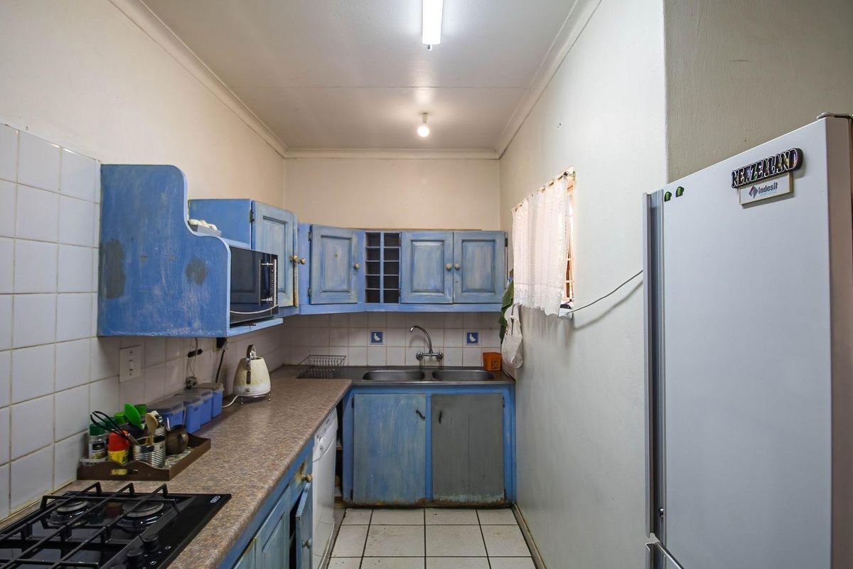 A compact kitchen featuring blue cabinetry, a double basin sink, tiled backsplash, and a built-in gas hob.