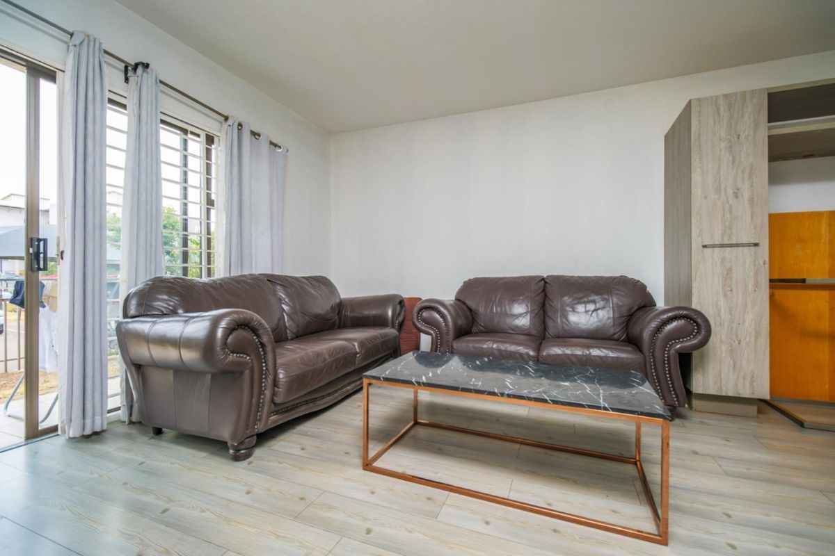 A living room area featuring light-toned wood-look flooring, a built-in storage cabinet, and sliding glass door access to an outdoor space.