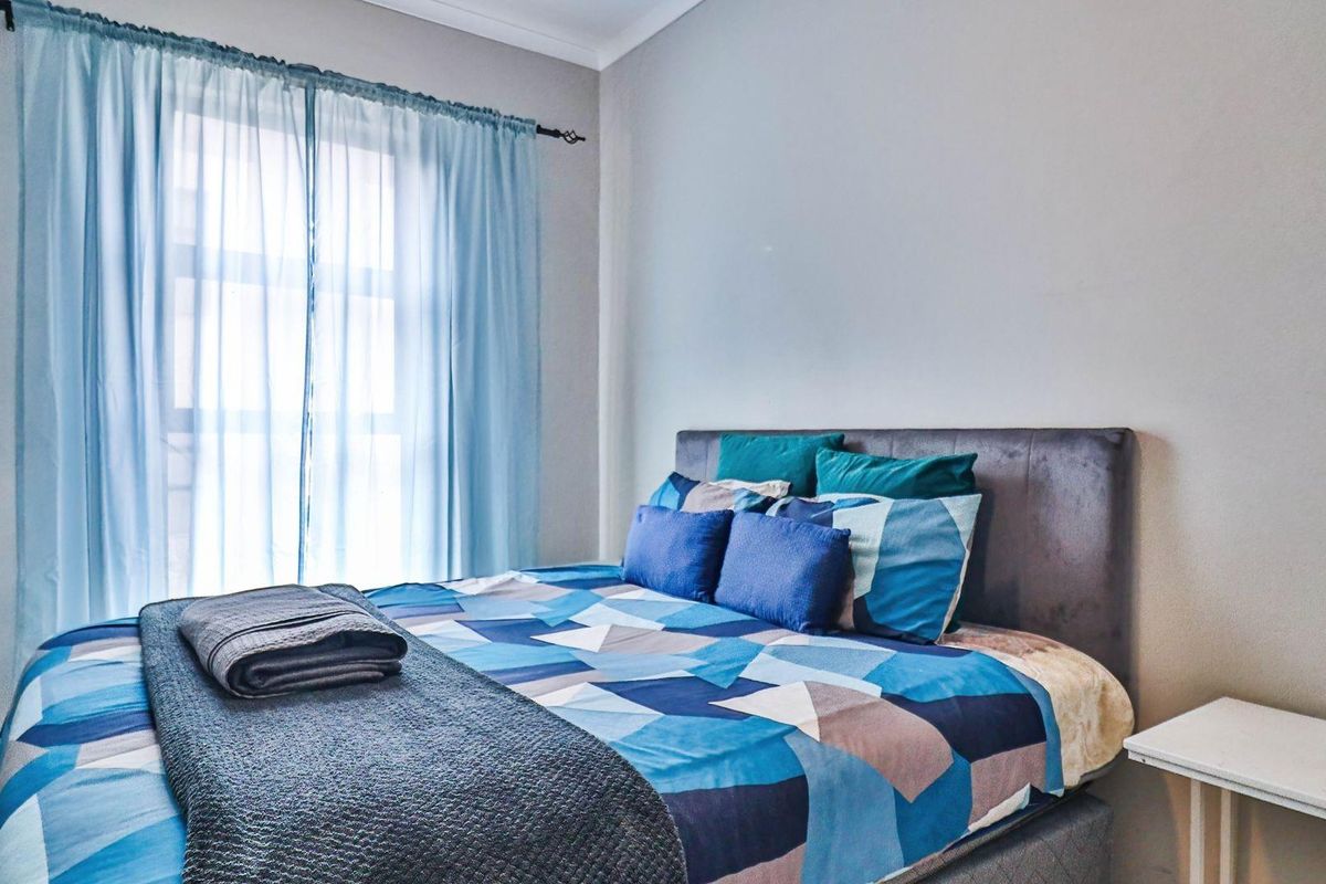A well-lit bedroom featuring neutral wall finishes and a window with curtain fixtures.