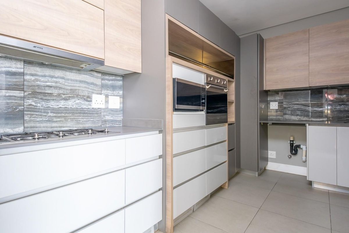 Modern kitchen featuring light wood and grey cabinetry, stone-look backsplash, built-in Smeg gas hob, extractor fan, and integrated oven and microwave.