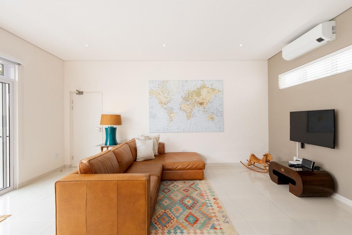 Bright and modern living room featuring tiled flooring, recessed lighting, and a wall-mounted air conditioning unit with access to the outdoor area.
