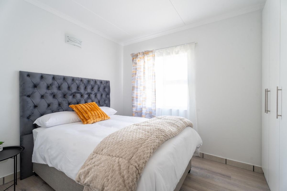 A well-maintained bedroom featuring laminate flooring, a built-in wardrobe, and neutral finishes, offering a clean and comfortable living space.