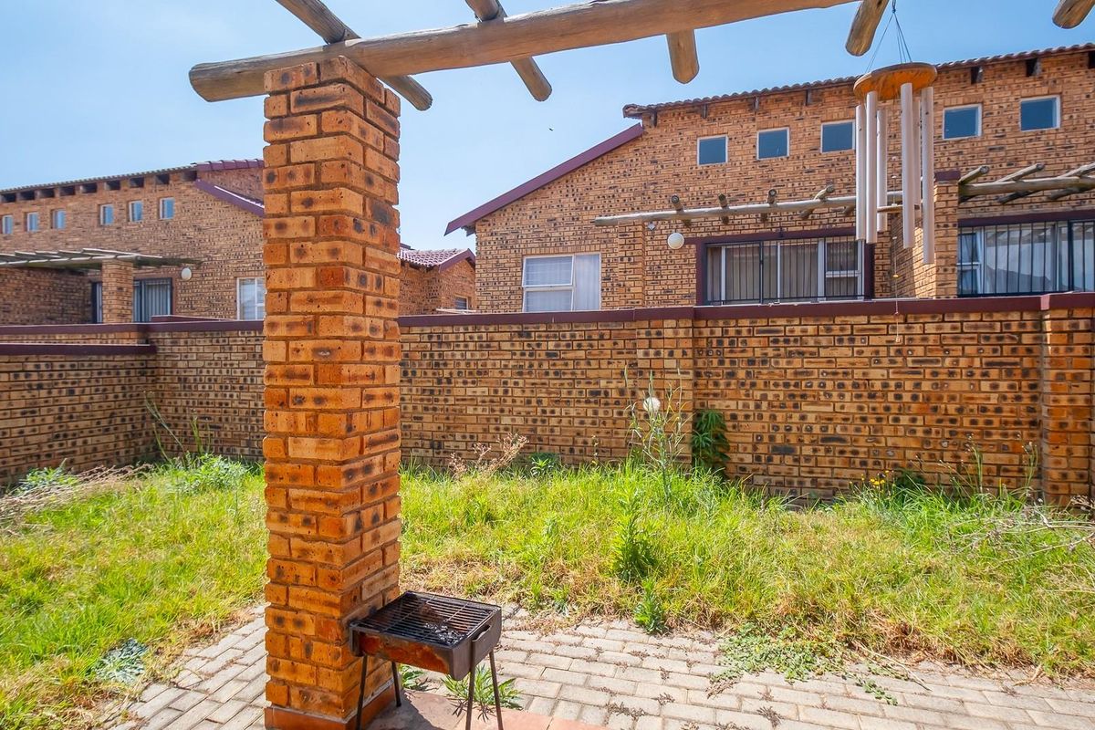 A private rear garden featuring a brick-built pergola, paved patio area, and perimeter brick walling, requiring landscaping and maintenance.