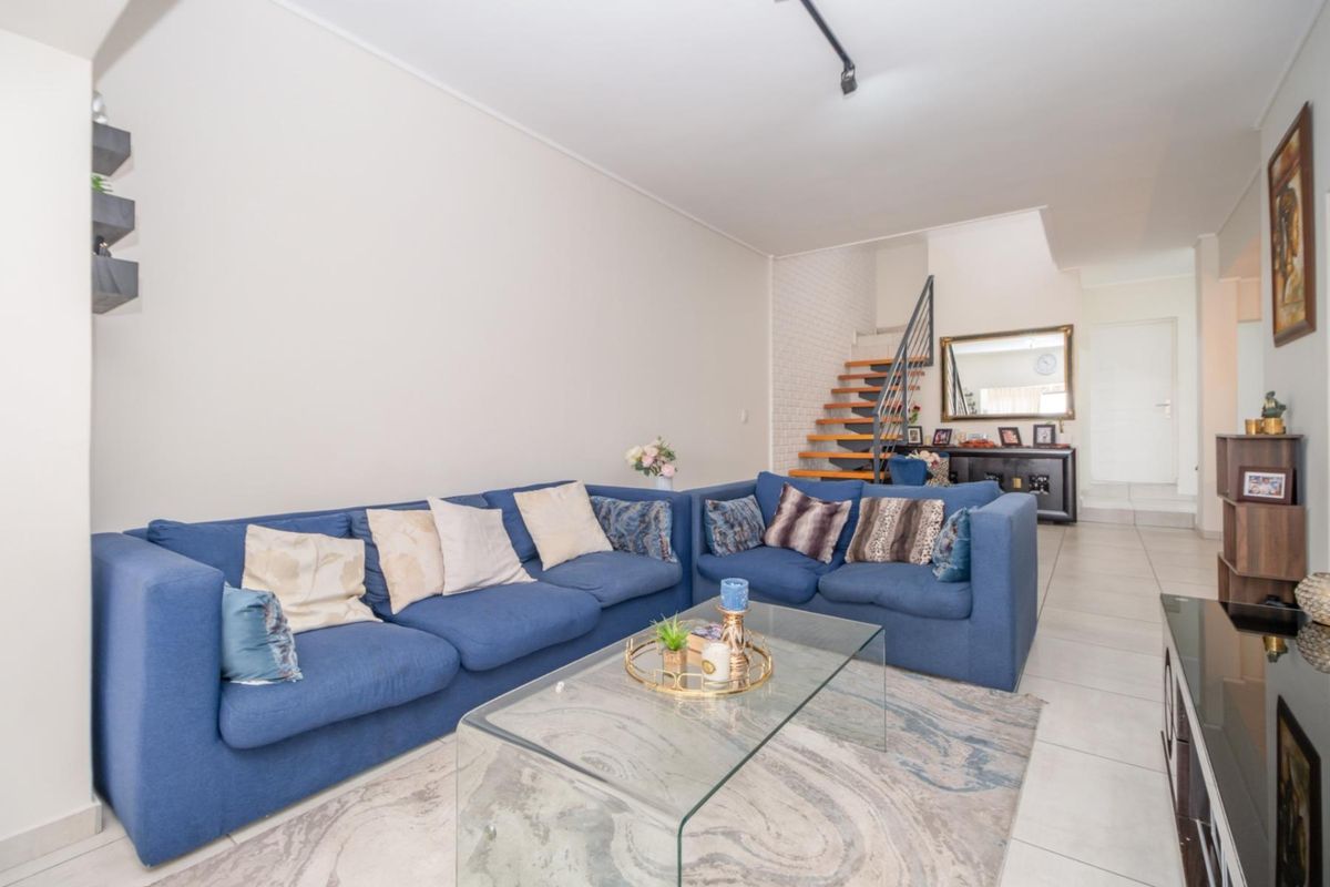 Open plan living area featuring tiled flooring and a staircase with timber treads and metal balustrade.
