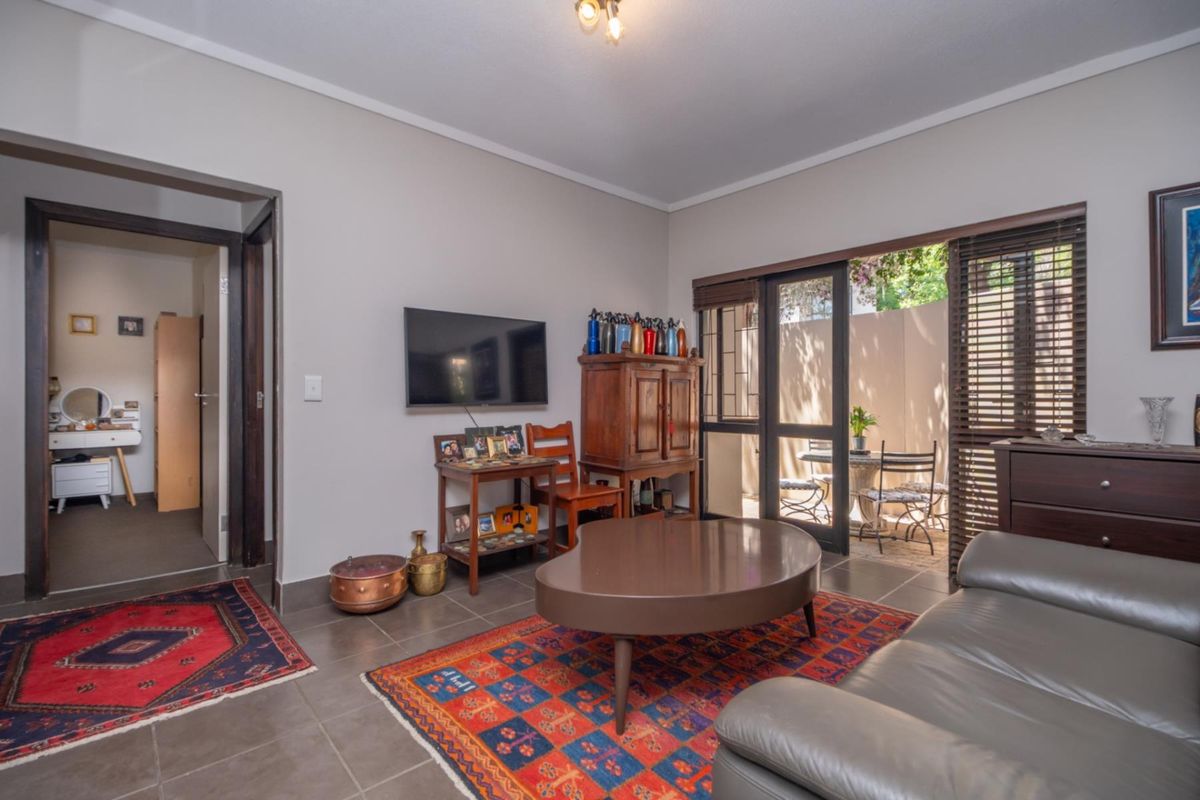 A living room featuring tiled flooring and sliding glass doors that open onto a private patio area.