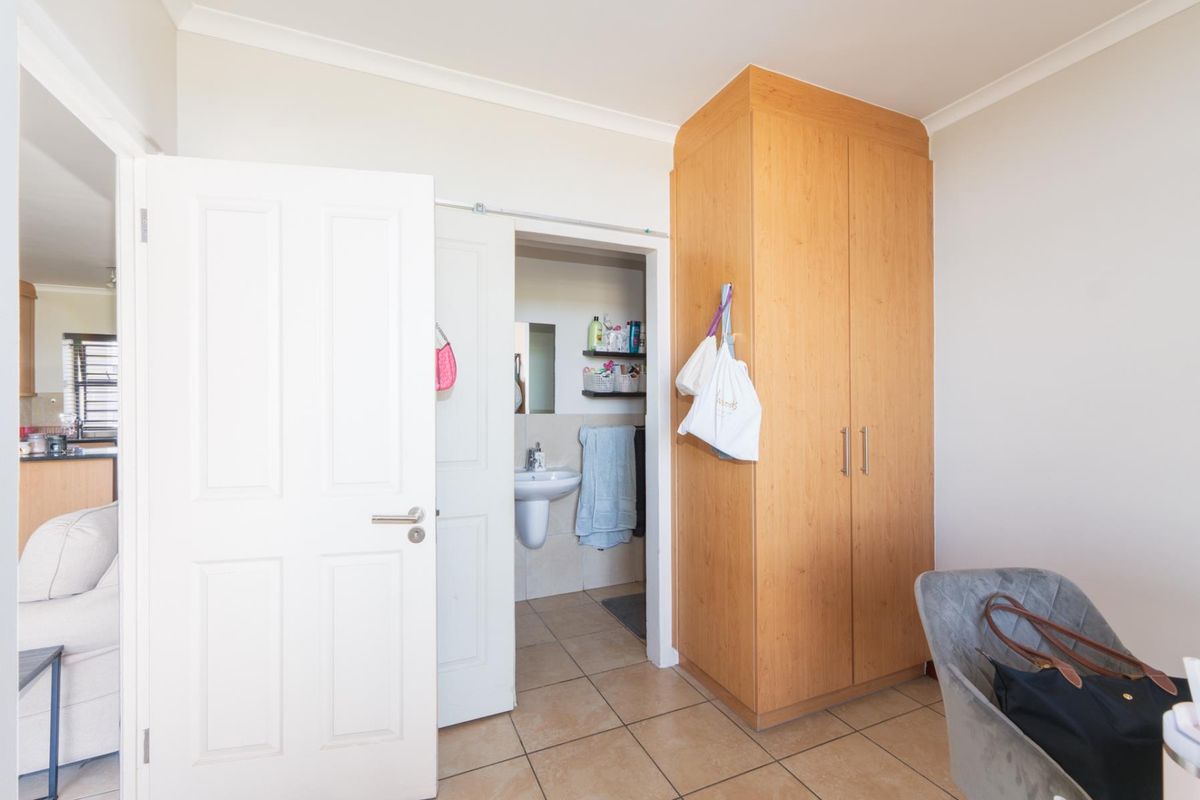 Bedroom featuring tiled flooring, a built-in wooden wardrobe, and direct access to an en-suite bathroom.