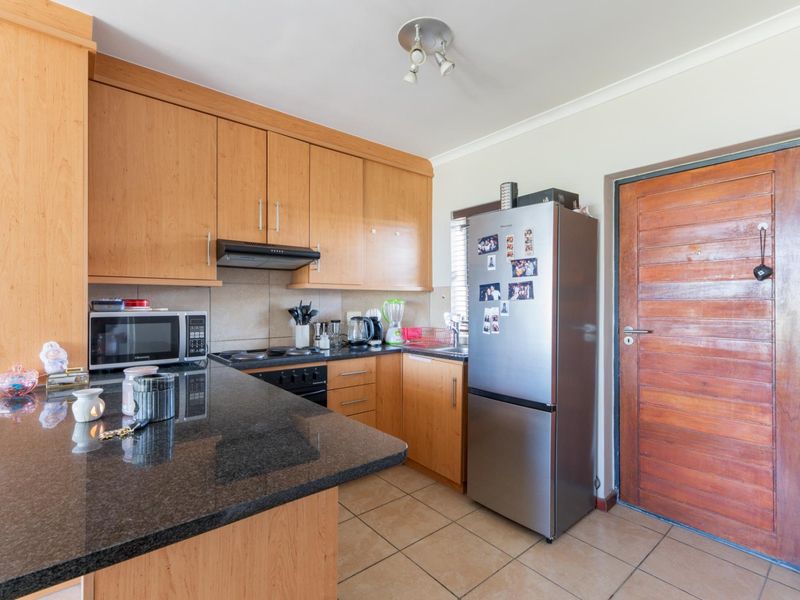 A functional kitchen featuring granite countertops, wooden cabinetry, built-in oven with extractor fan, and tiled flooring, providing a practical workspace.