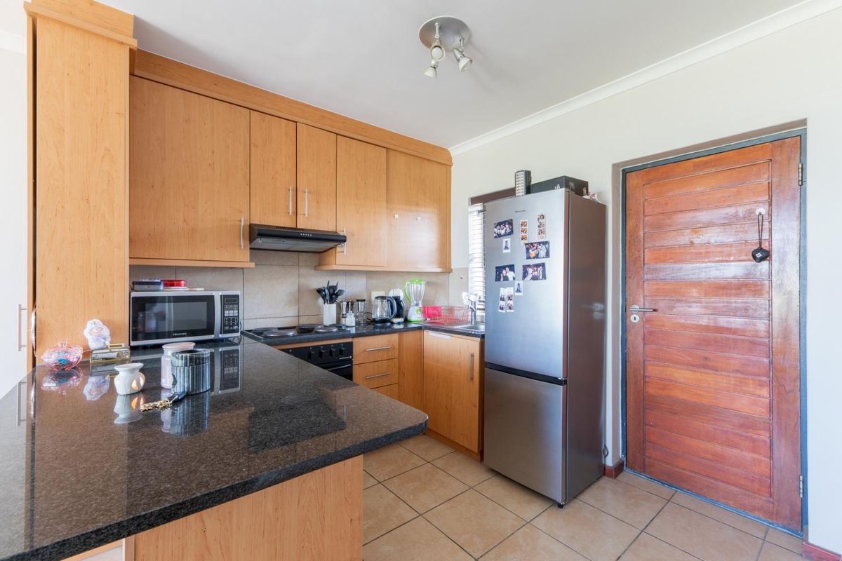A functional kitchen featuring granite countertops, wooden cabinetry, built-in oven with extractor fan, and tiled flooring, providing a practical workspace.