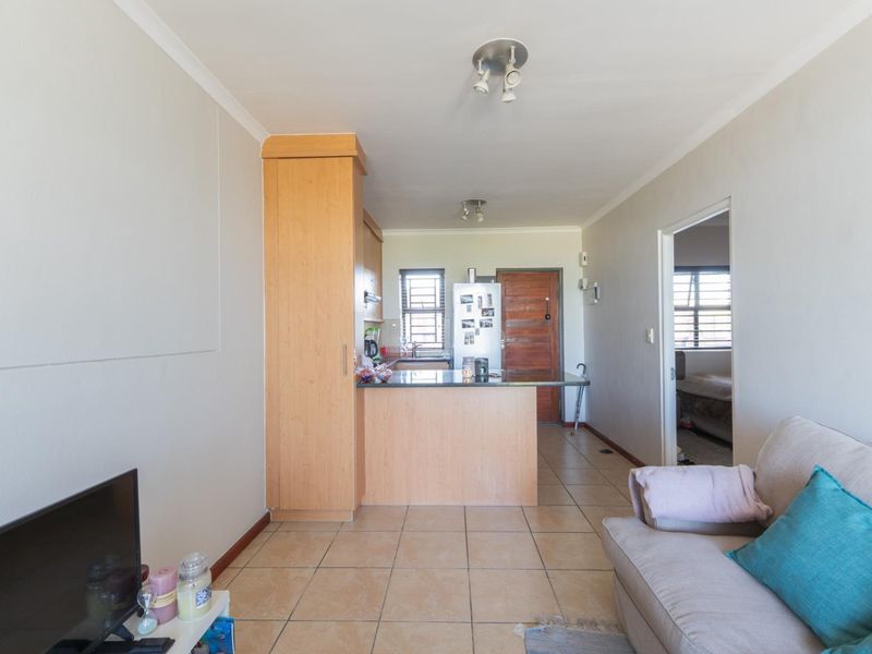 Open-plan living and kitchen area featuring tiled flooring, built-in cabinetry with granite countertops, and direct access to an adjacent room.
