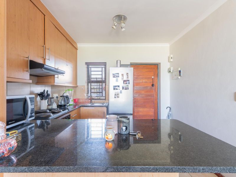 A functional kitchen featuring wooden cabinetry, granite countertops, and a tiled backsplash, providing a practical workspace for daily cooking and meal preparation.