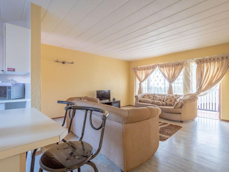 Open-plan living area featuring laminate flooring, neutral wall finishes, and direct access to a balcony through sliding glass doors.
