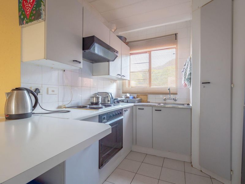 Compact kitchen featuring built-in cabinetry, electric oven and hob, tiled backsplash, and functional workspace with a window for natural light.