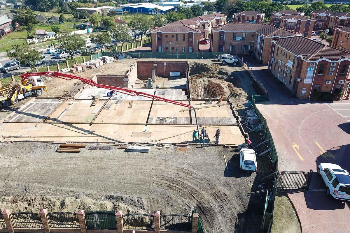 Aerial view of a commercial property construction site showing foundation work in progress with concrete pumping equipment on site.