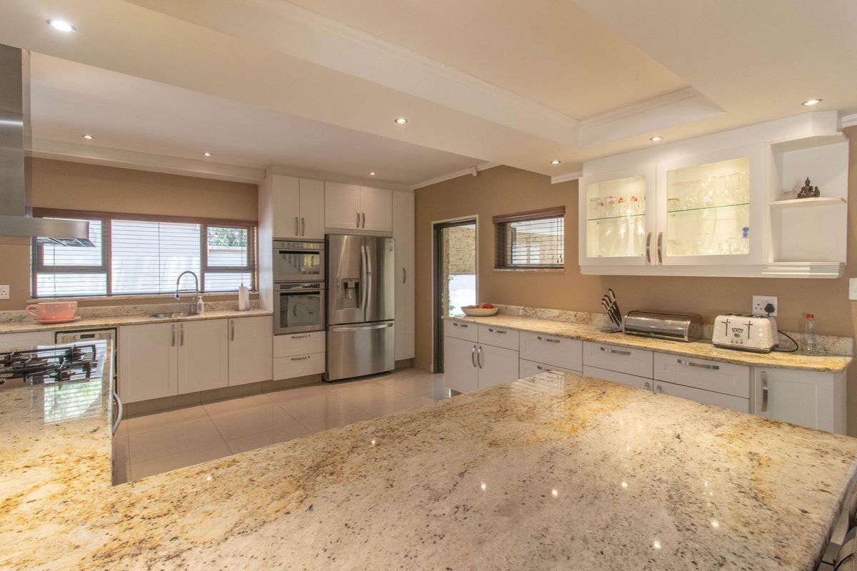 Modern kitchen featuring granite countertops, white cabinetry, built-in oven, stainless steel appliances, and recessed ceiling lighting.