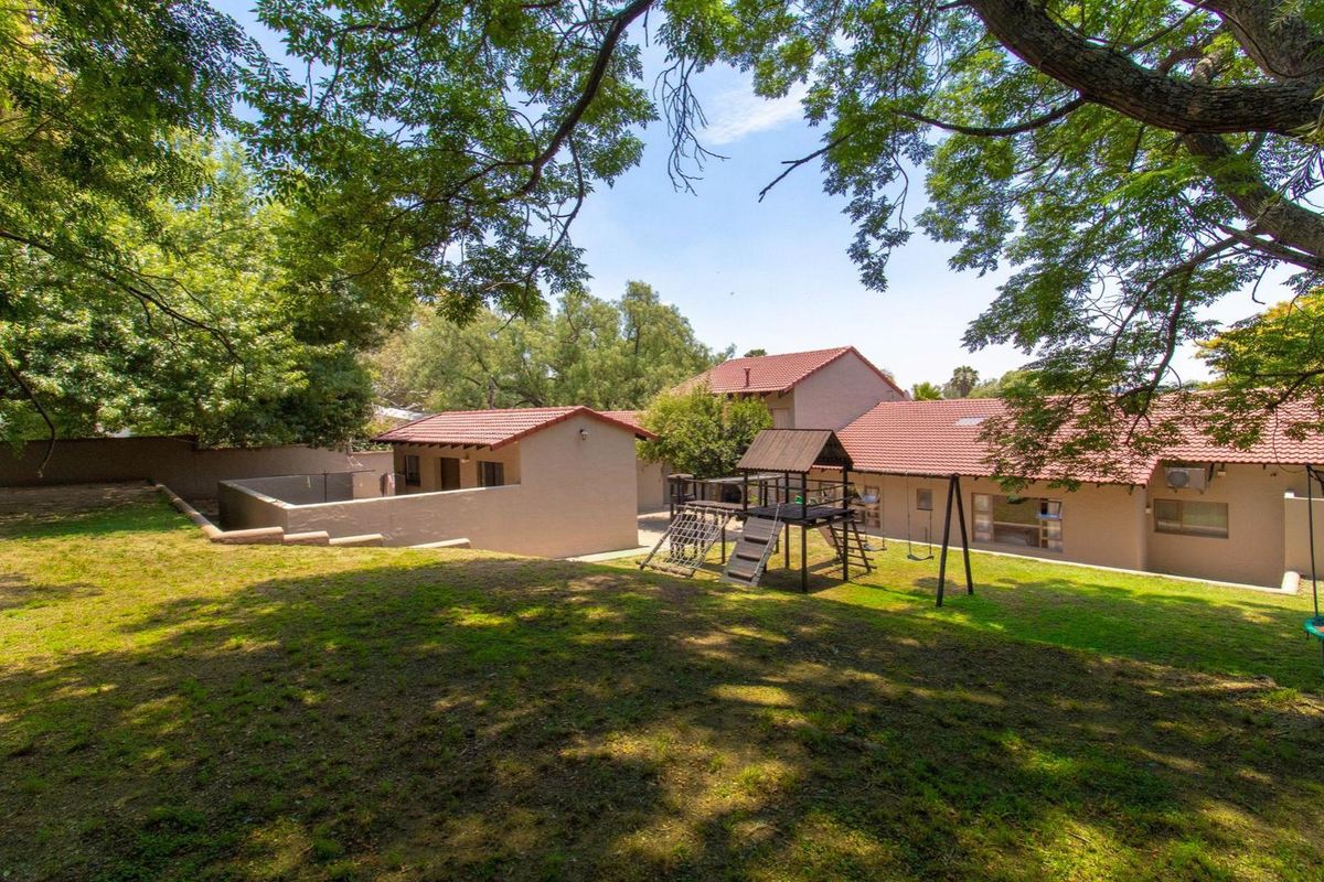 Spacious rear garden area featuring mature trees, a lawn, and views of the property's exterior elevations with terracotta tiled roofing.