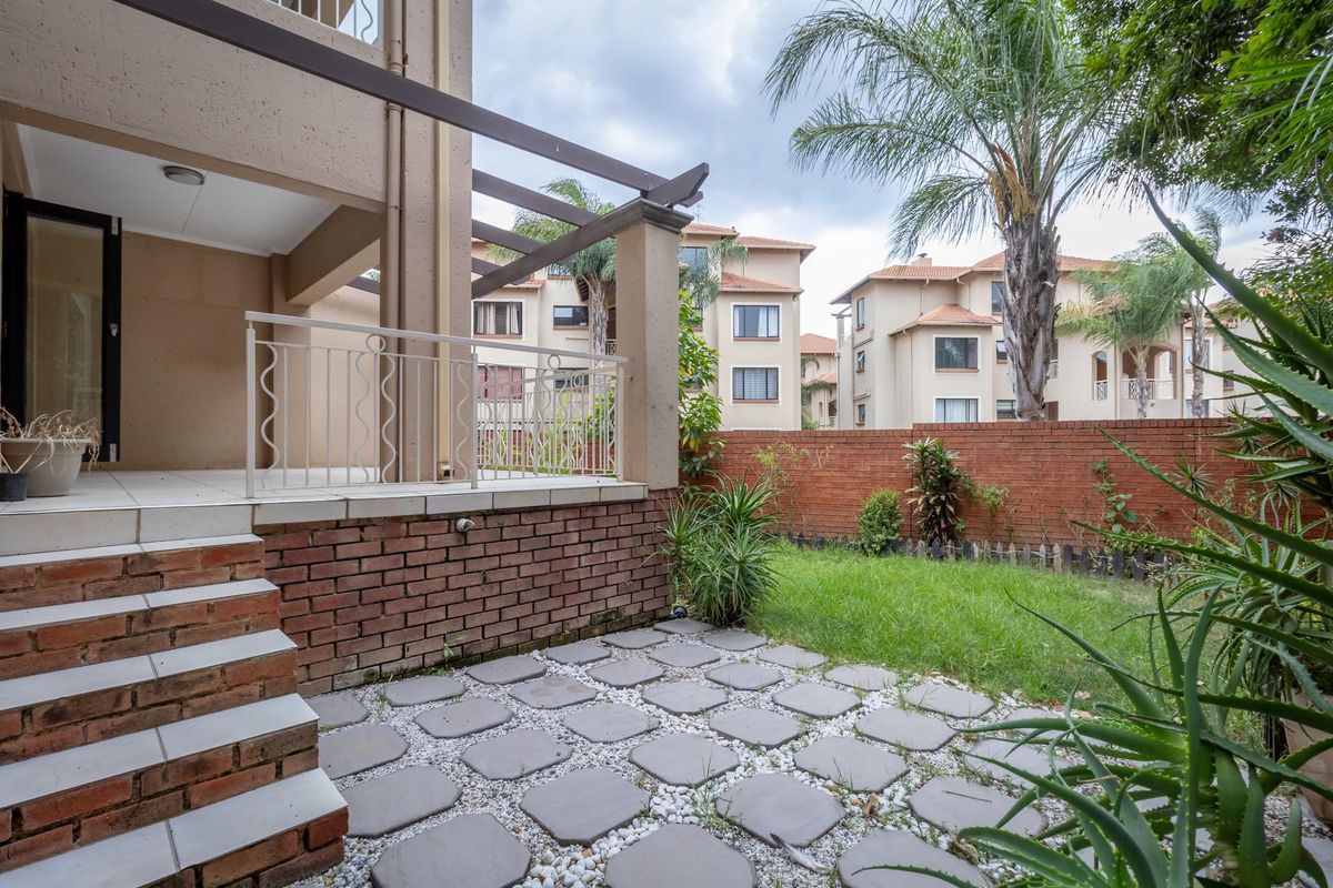 A private ground-floor patio area featuring a paved section, small garden, and a raised terrace with a metal balustrade.