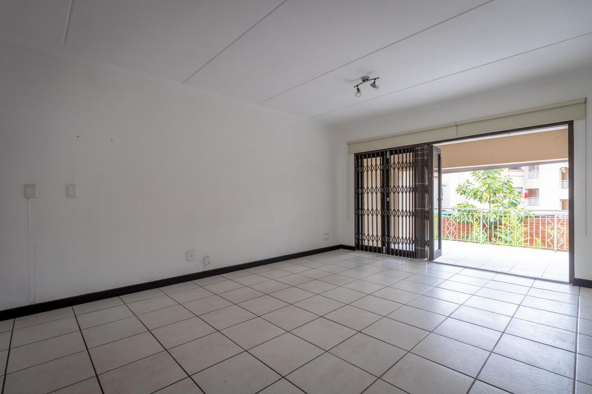 Spacious, tiled living area featuring large sliding doors that open onto a private balcony, providing ample natural light and seamless indoor-outdoor flow.