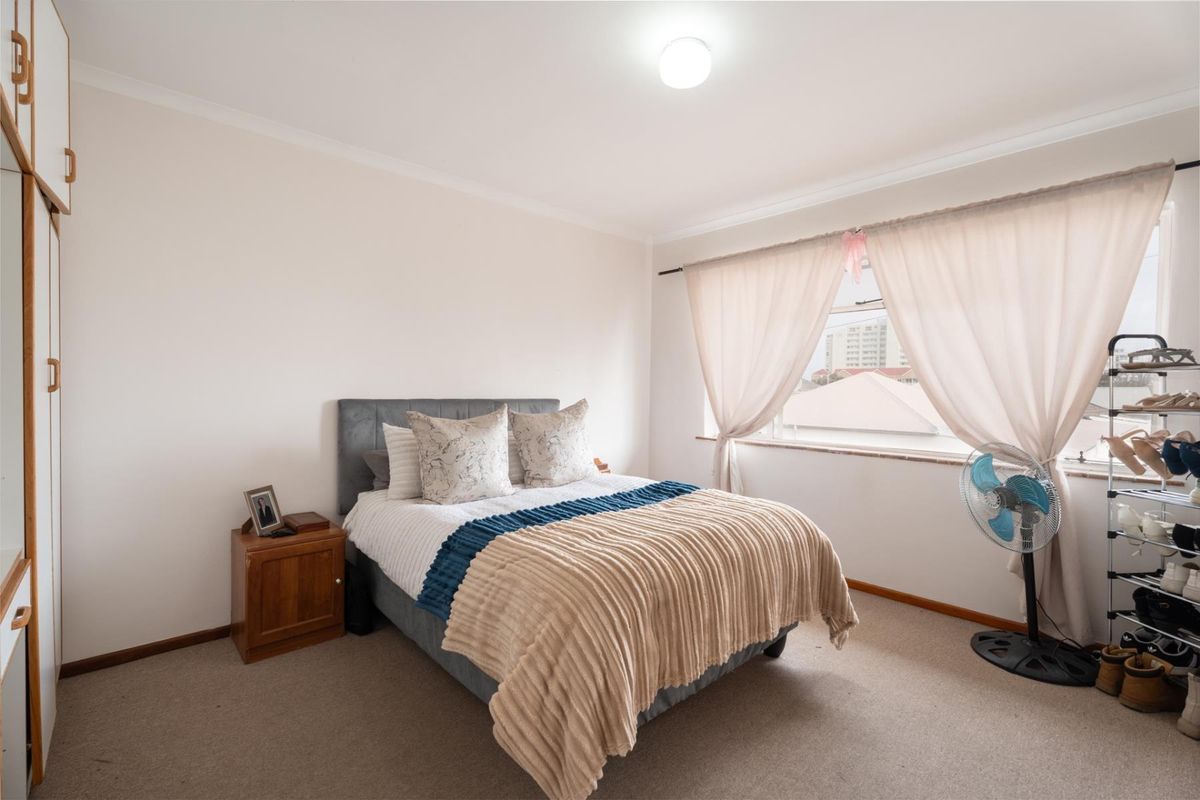 A well-lit bedroom featuring neutral walls, carpeted flooring, and built-in cupboards, offering a comfortable and functional living space.
