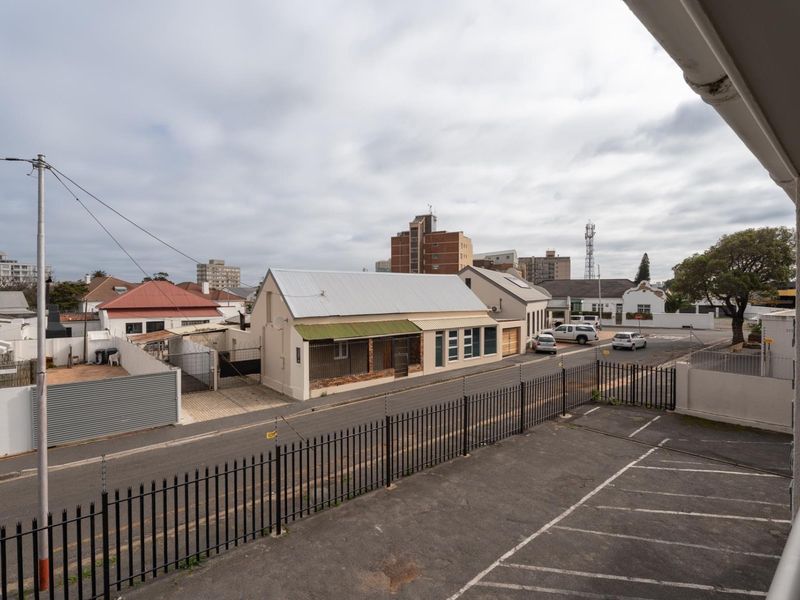 Elevated view overlooking a paved parking area, perimeter fencing, and surrounding neighborhood streetscape.